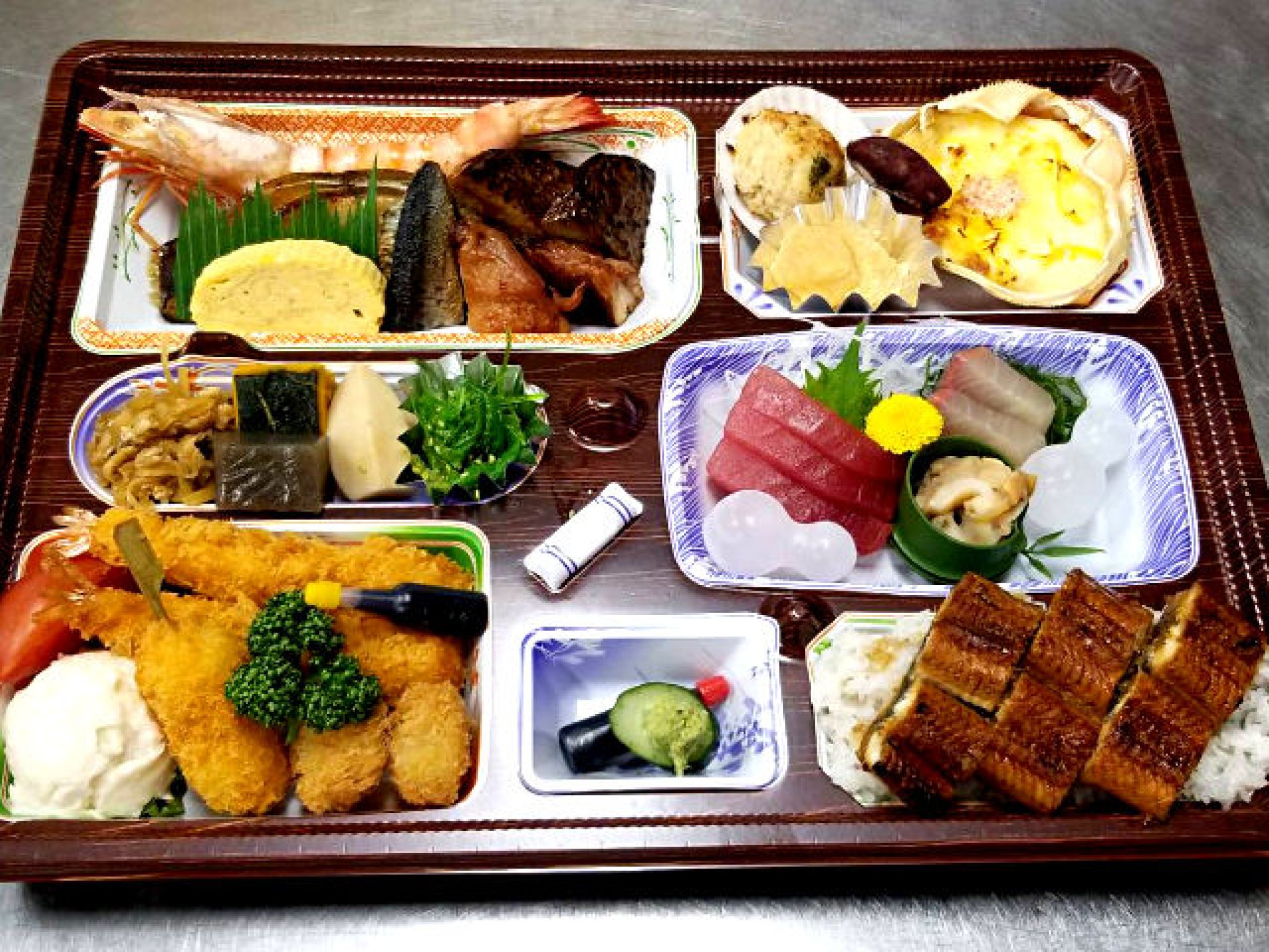 仕出し弁当3,240円～3,780円の一例。鰻、カニグラタン、海老が付いた豪華な内容。